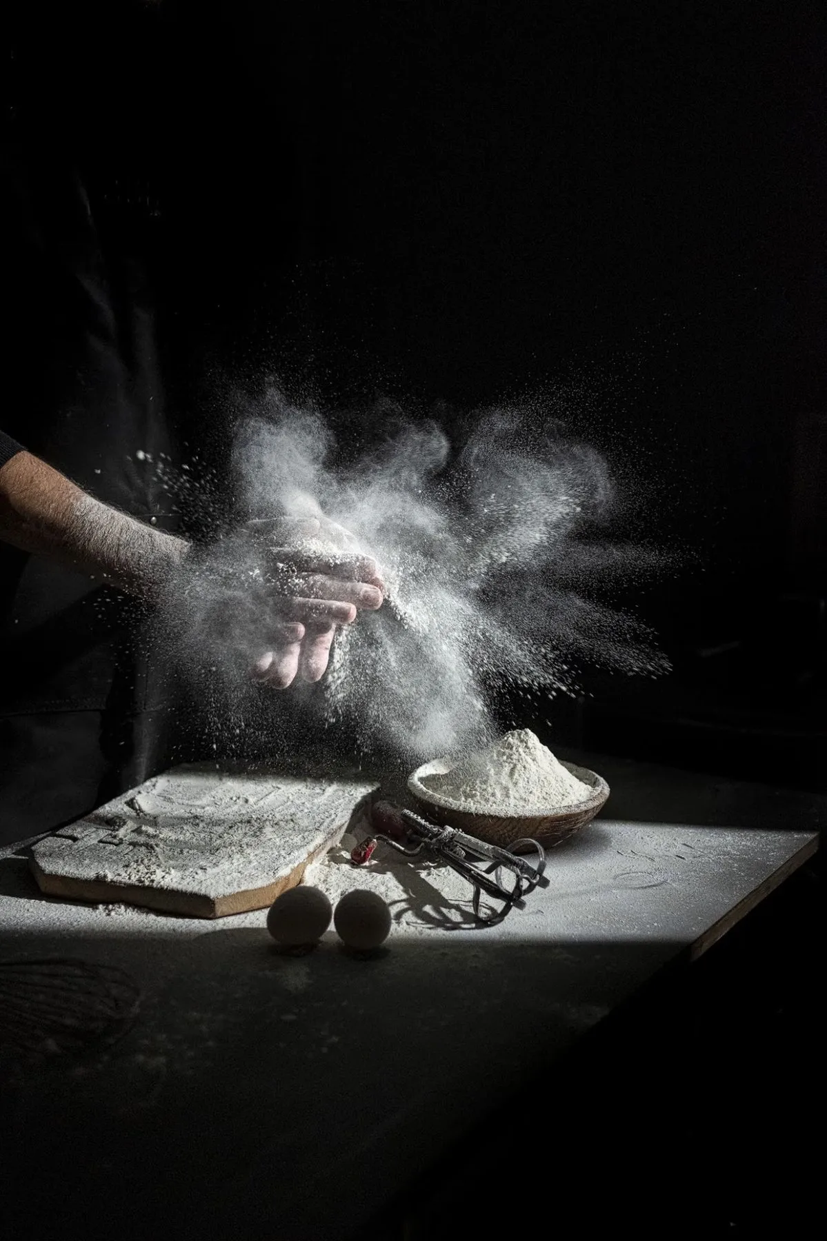 Flour falling onto a pastry board in low light
