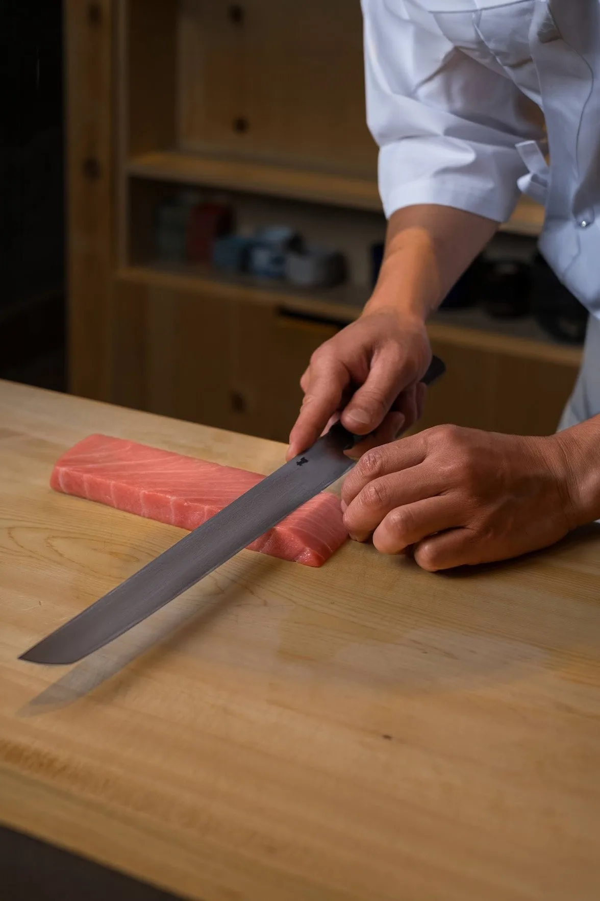 Chef slicing tuna on a wooden board