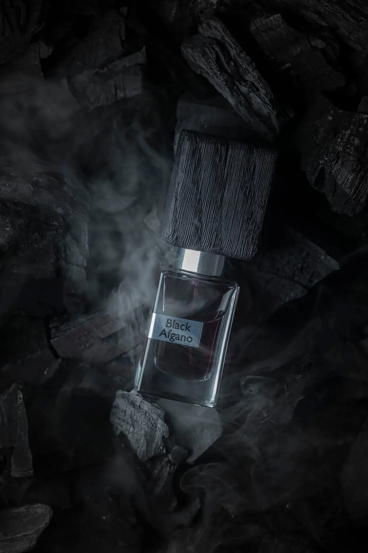 Perfume bottle in smoke on black stone