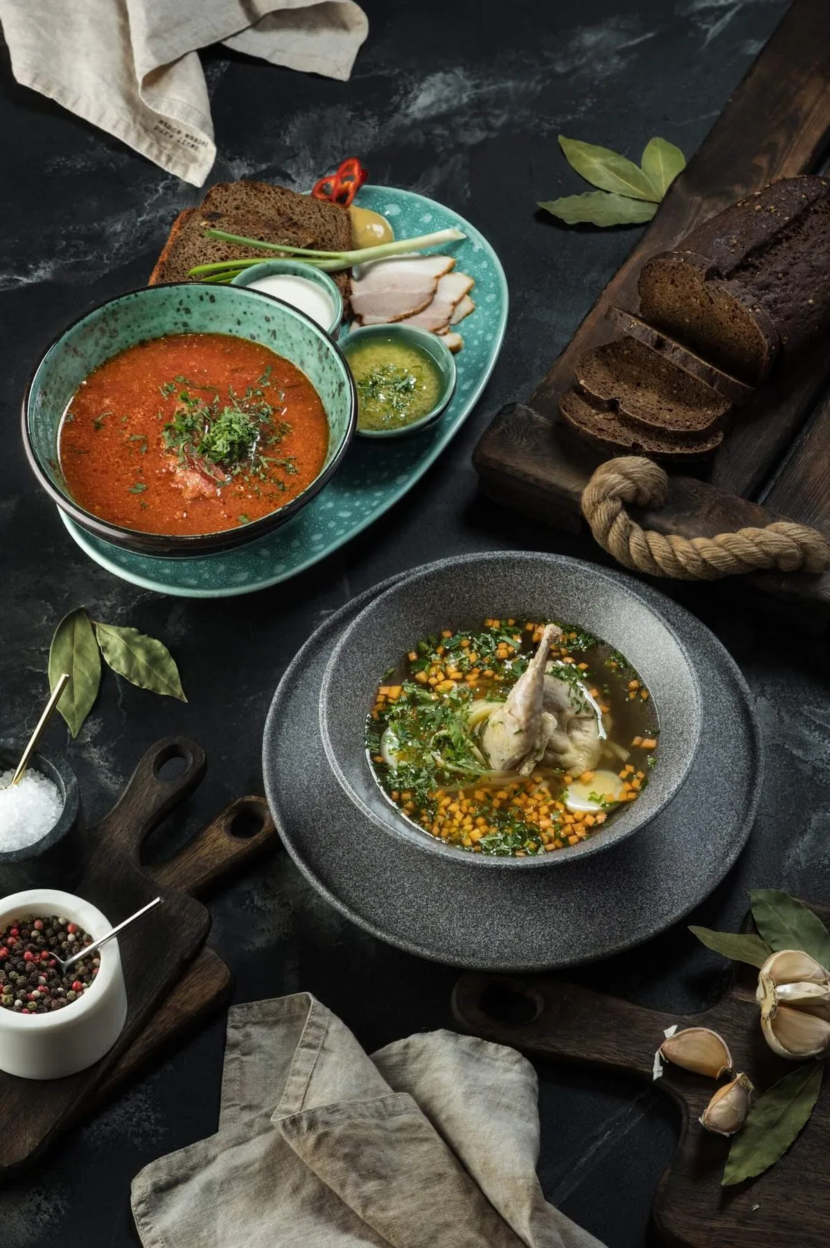 Soups and bread on a dark table, top view