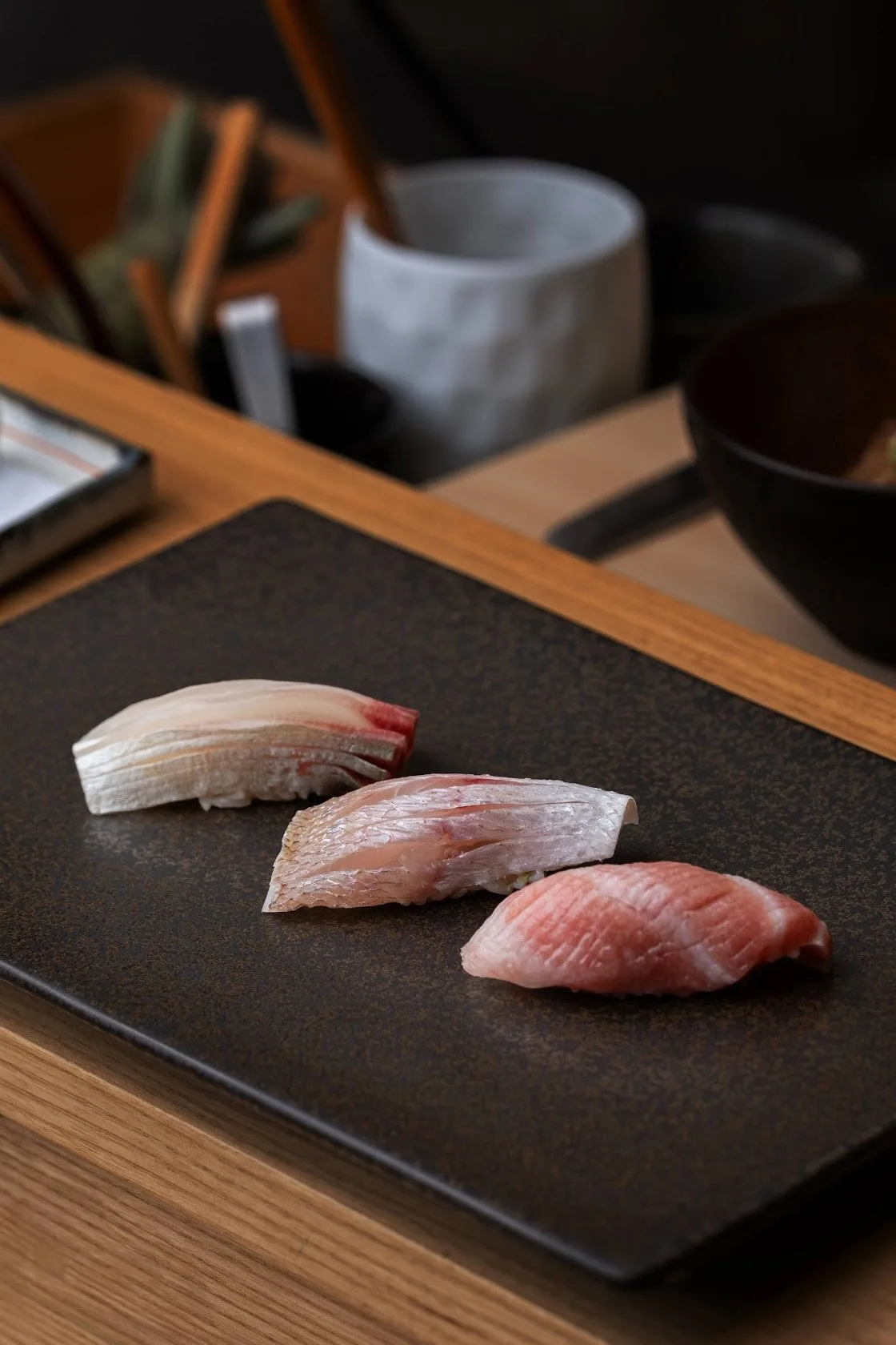 Three nigiri on a black slate