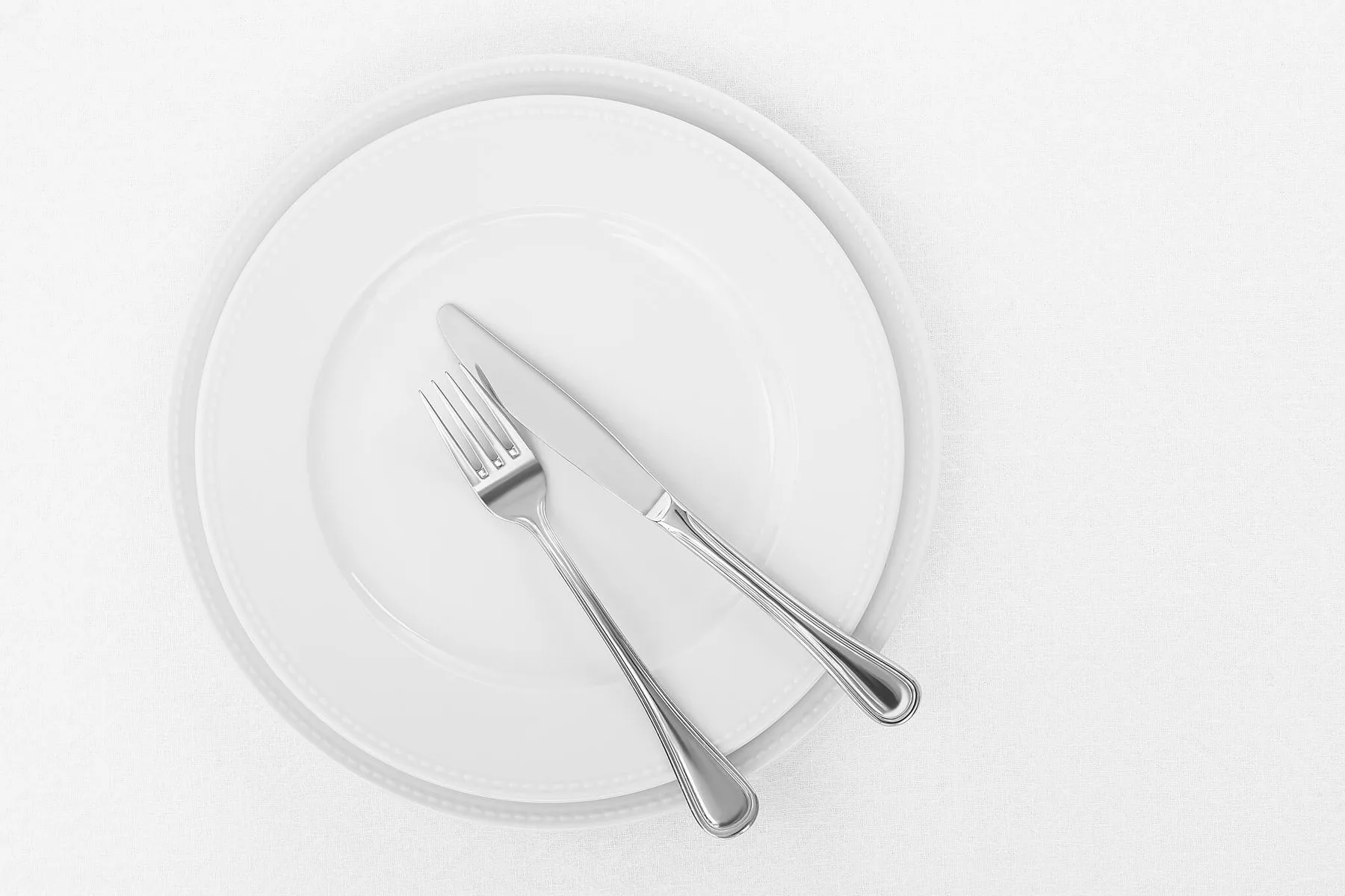 Empty white plate with a fork and knife